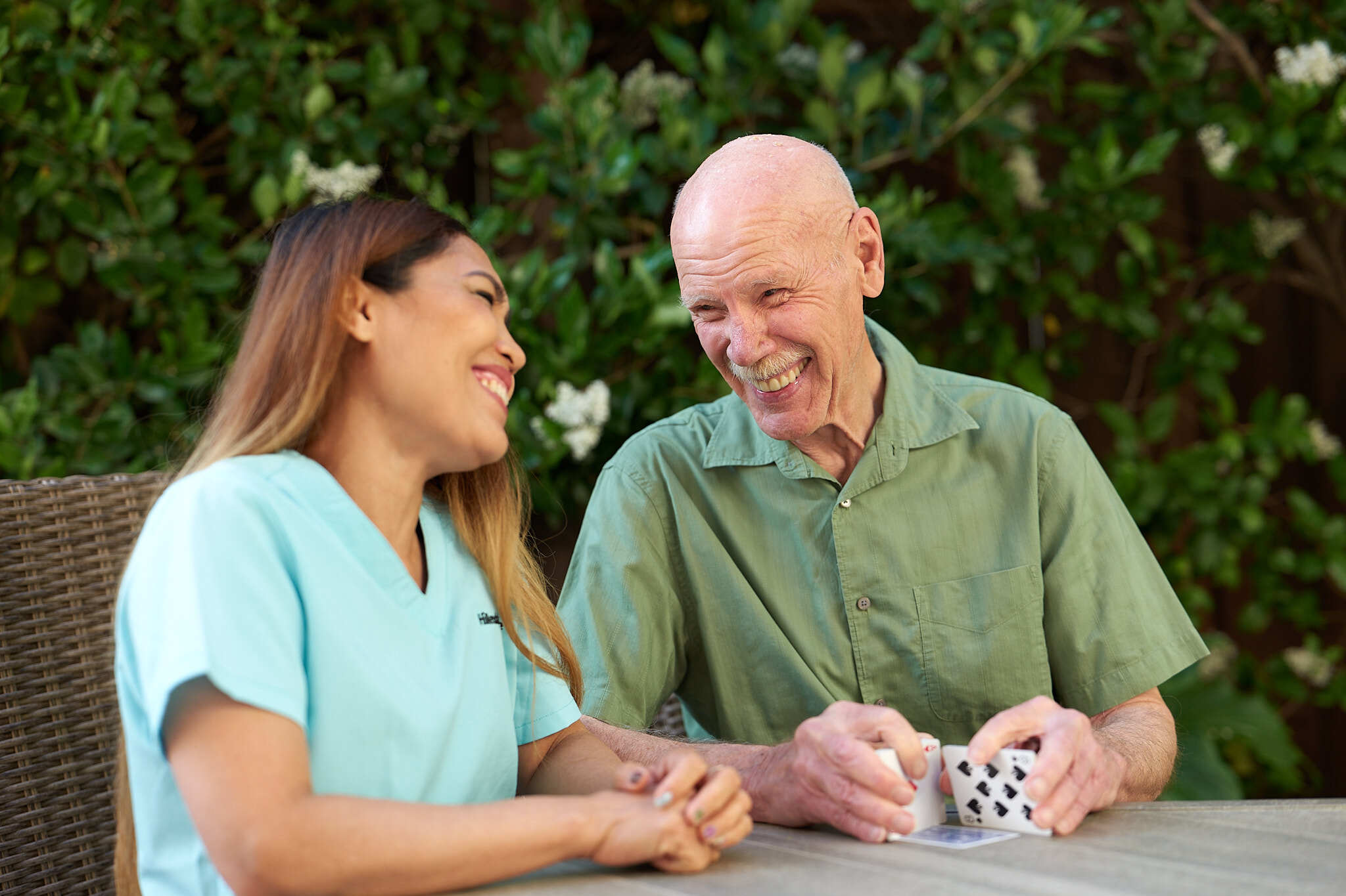 Patient and caregiver laughing while playing cards.